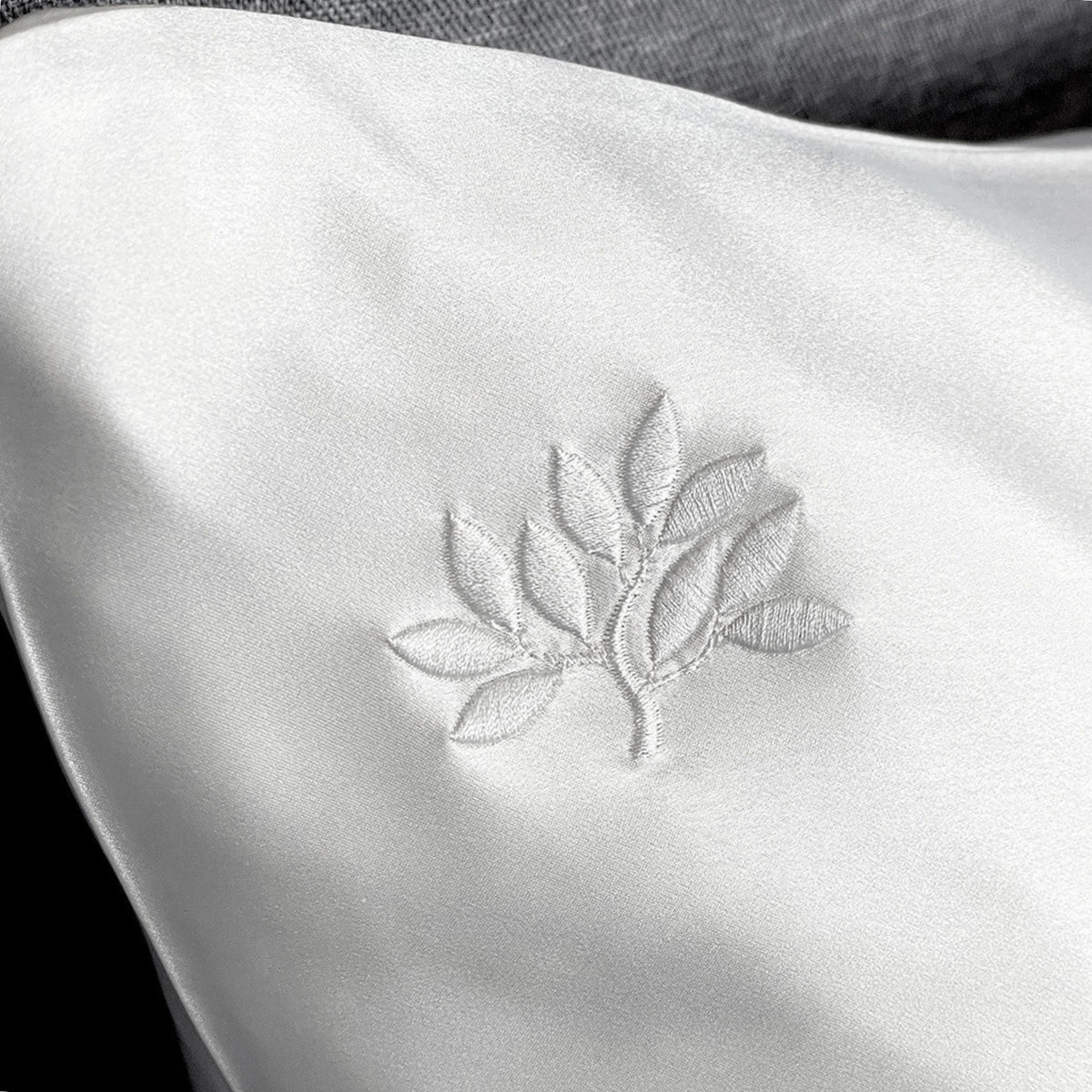 Close-up of a white 22 Momme silk pillowcase with an elegant embroidered leaf design