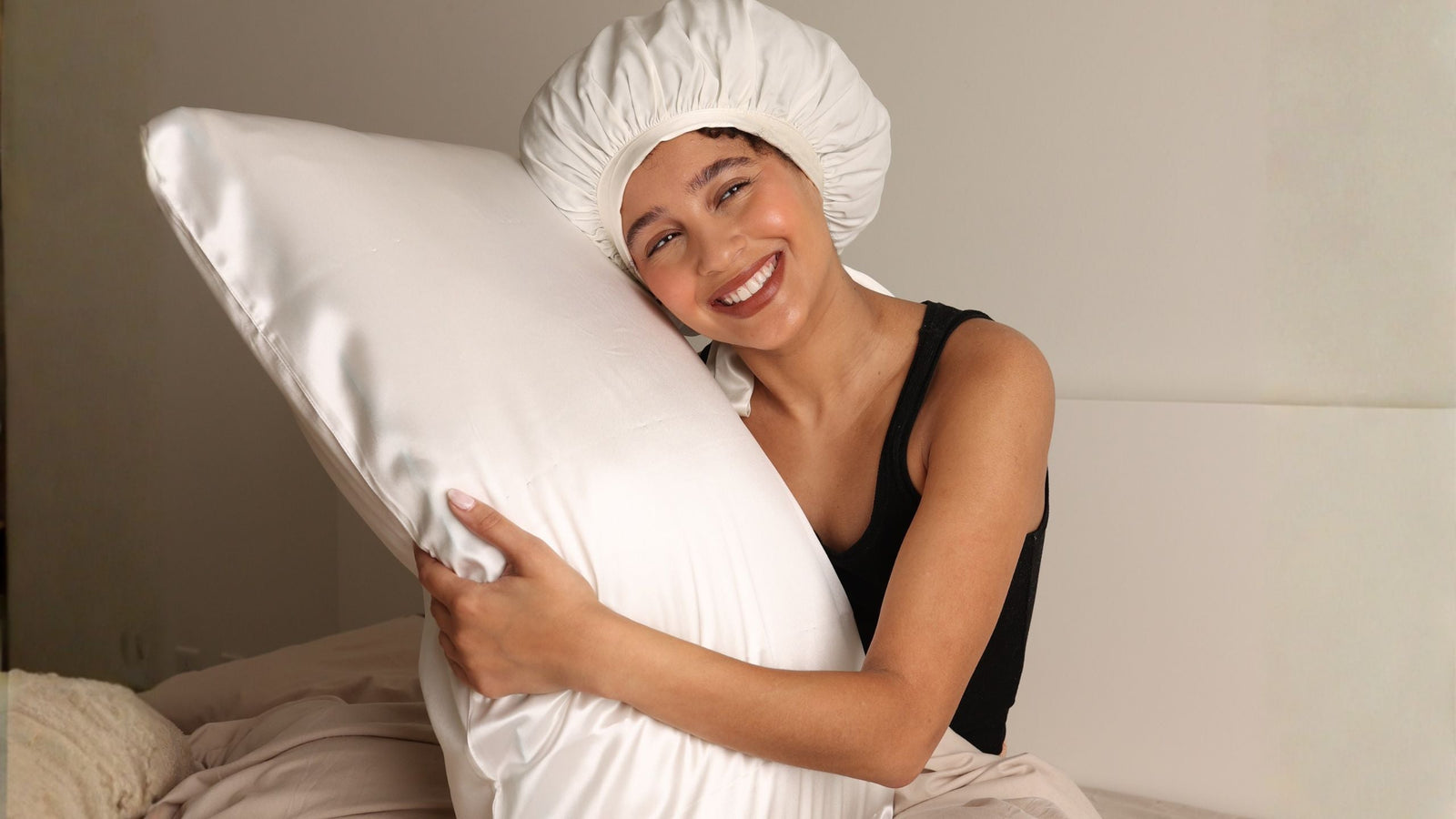Woman in  sleep bonnet hugging a silk pillowcase