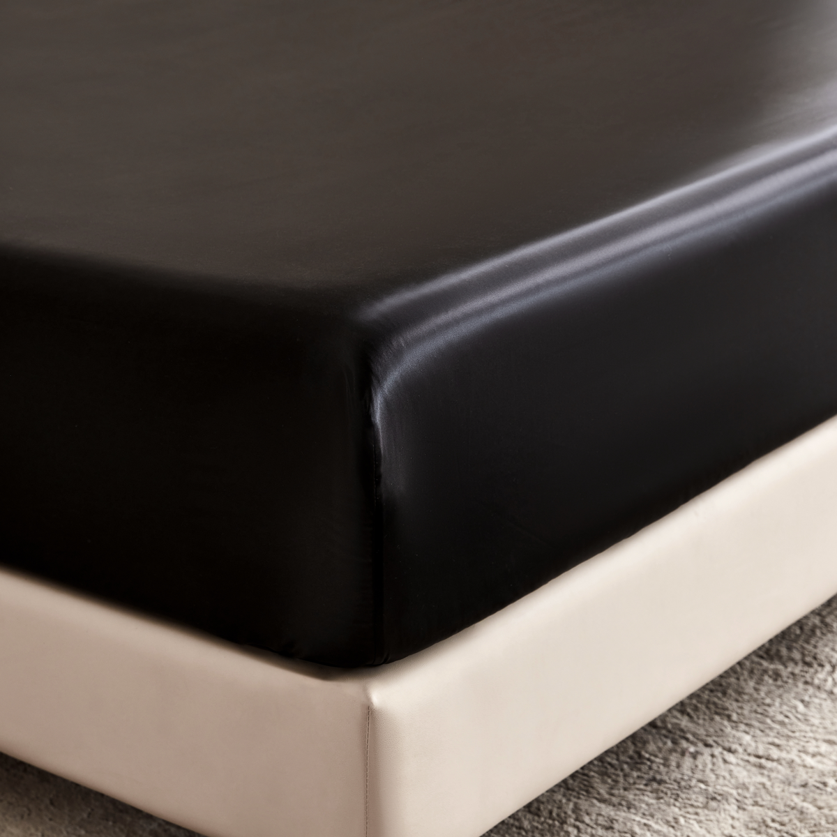 Black fitted sheet on a bed corner with a neutral background