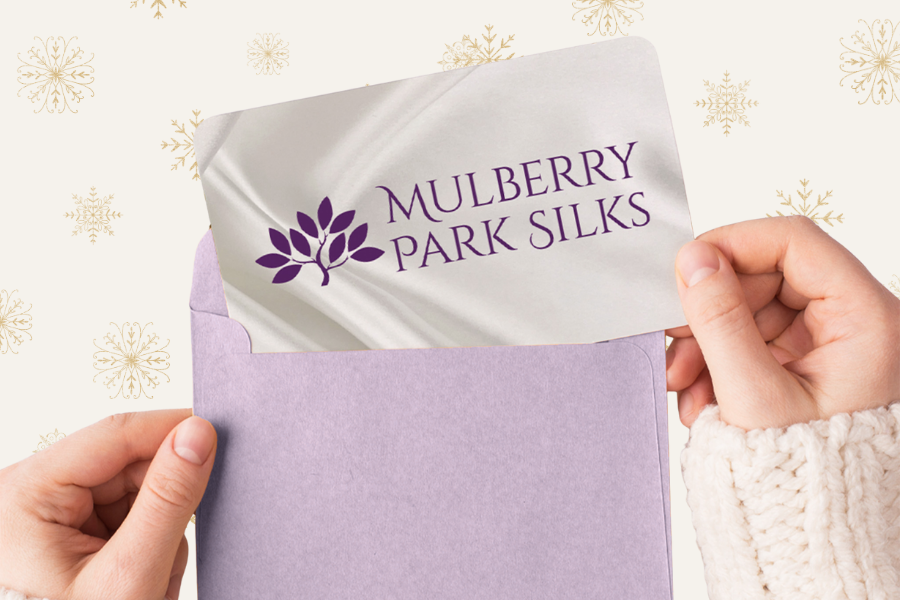 Purple silk fabric with 'Mulberry Park Silks' logo on a white card against a decorative background.