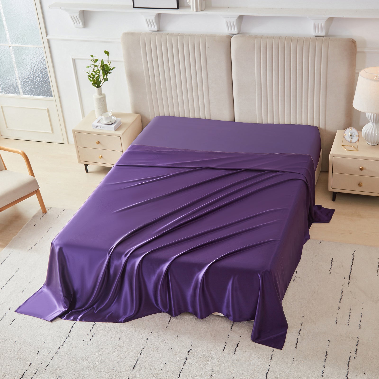 Plum silk flat sheet draped over a neatly made bed in a bright, modern bedroom