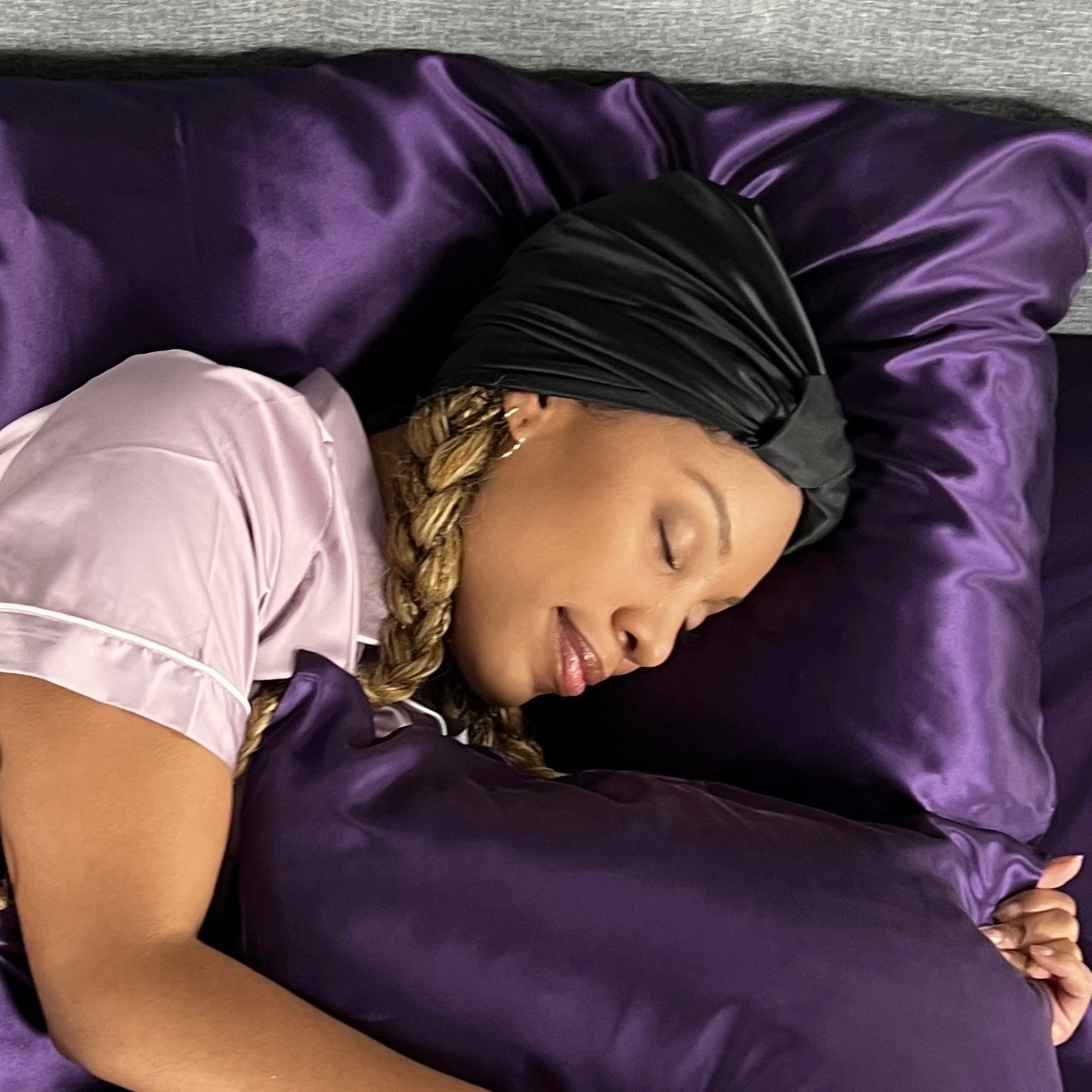 Woman sleeping on silk with a black silk head scarf to protect hair