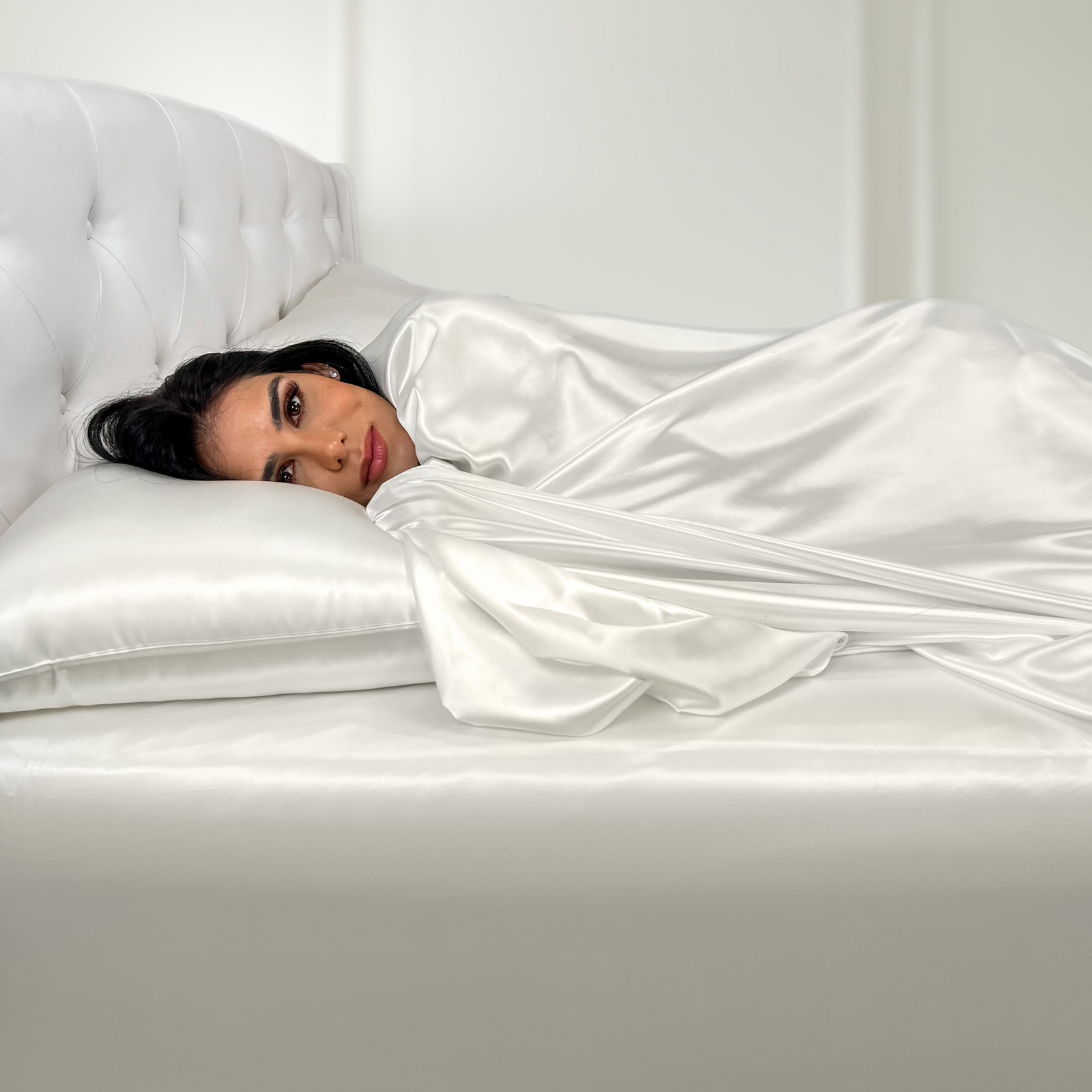 22 momme silk fitted sheet in Ivory on bed with upholstered headboard in a cozy bedroom setting