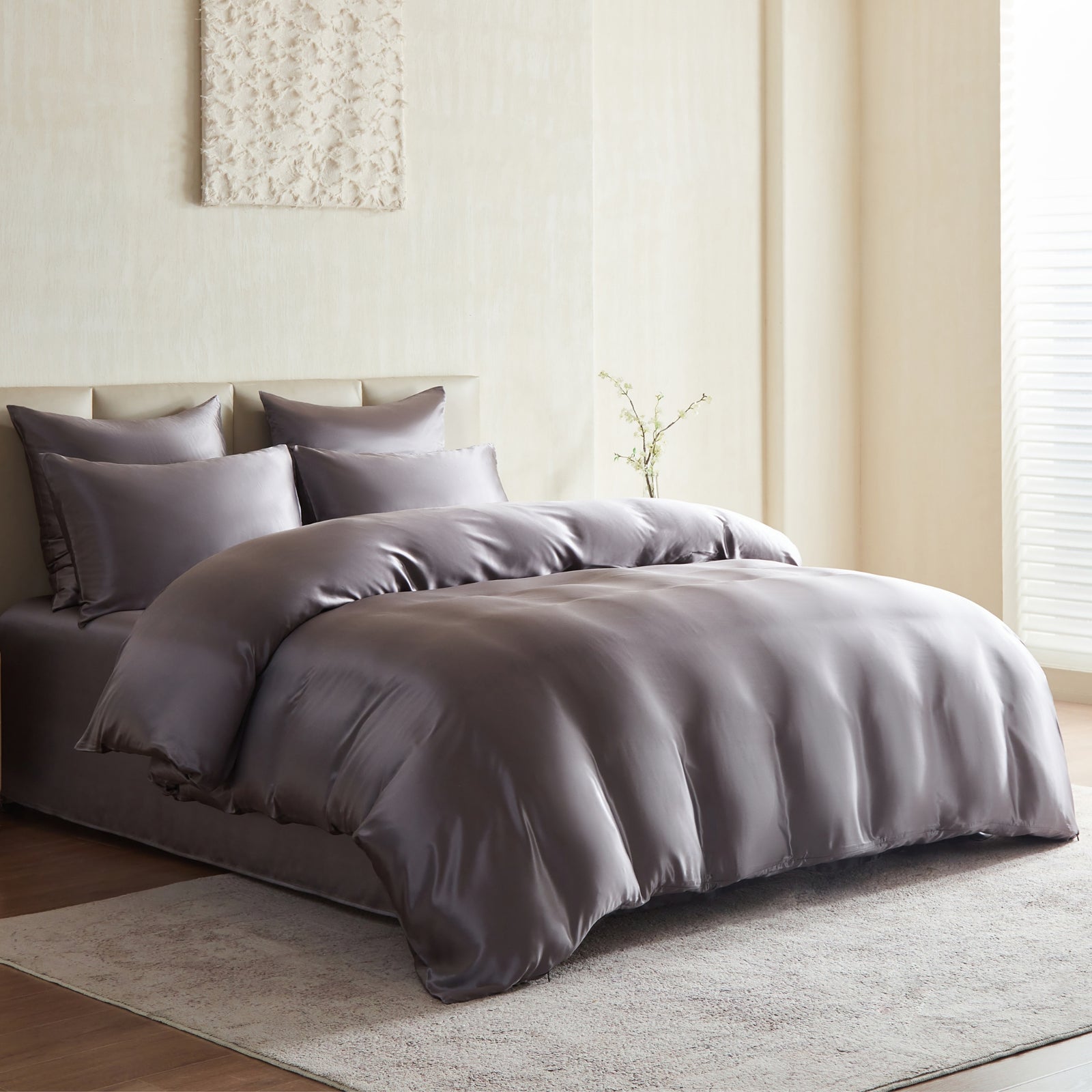 Gray silk bedding set on a bed in a bedroom with neutral decor