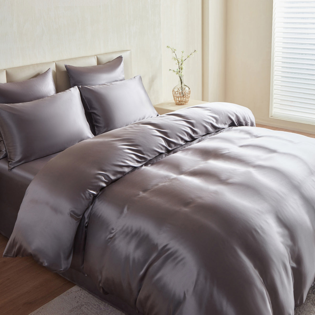 Gray silk comforter set on a bed in a bedroom with light decor.