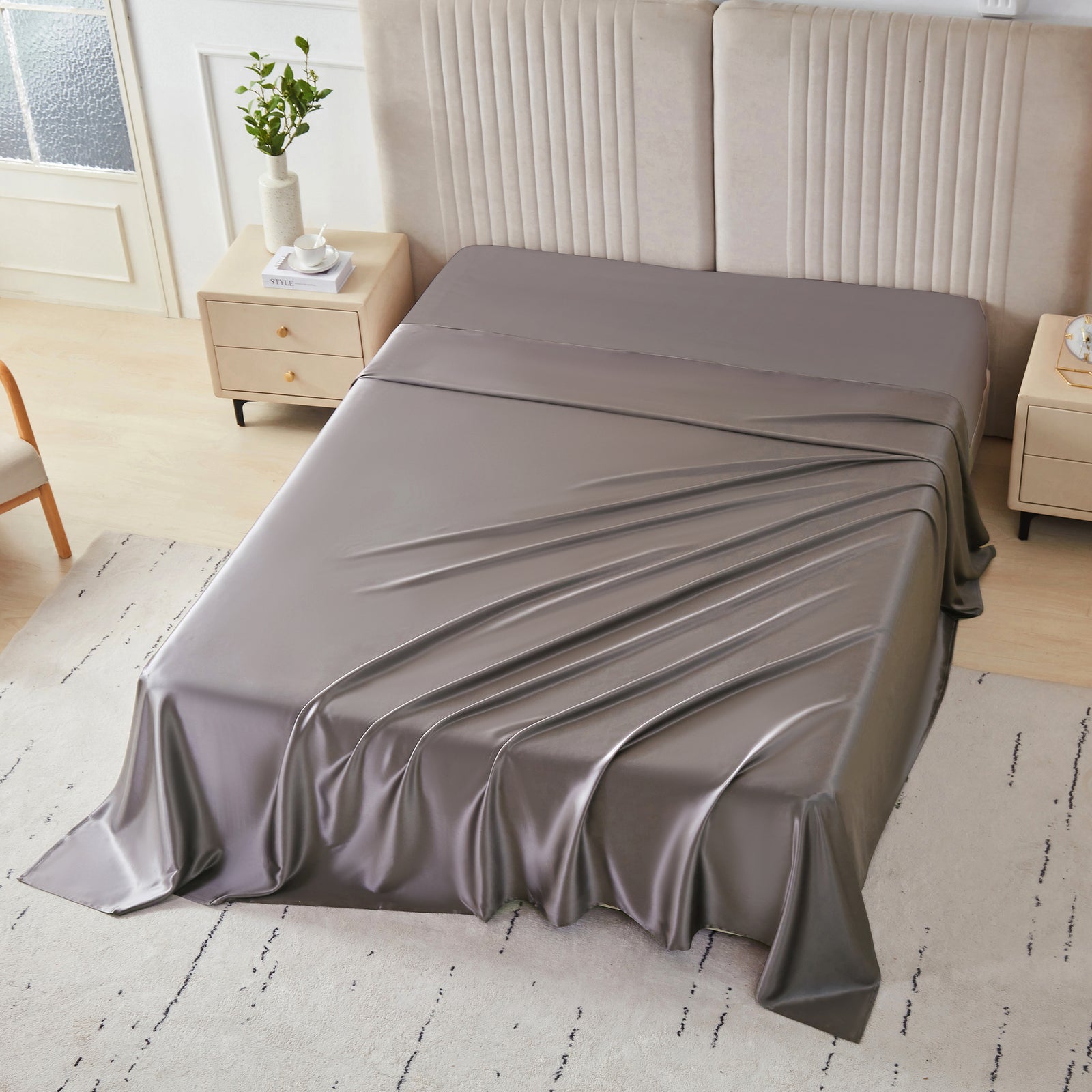 Gunmetal silk flat sheet draped over a neatly made bed in a bright, modern bedroom