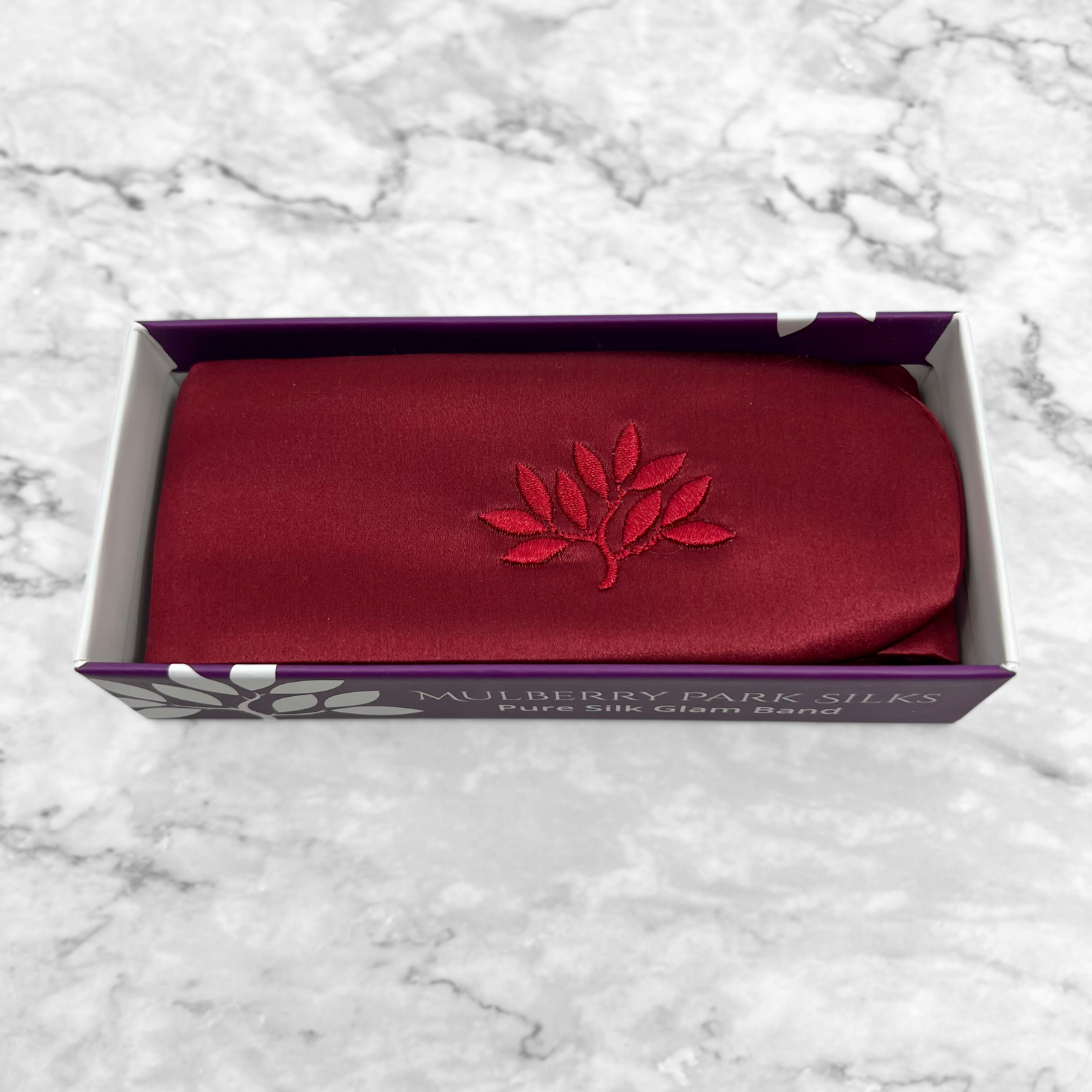 Silk Glam Band - Cabernet by Mulberry Park Silks: A deep-red, embroidered silk headband in a branded box on marble, showcasing luxury haircare elegance.