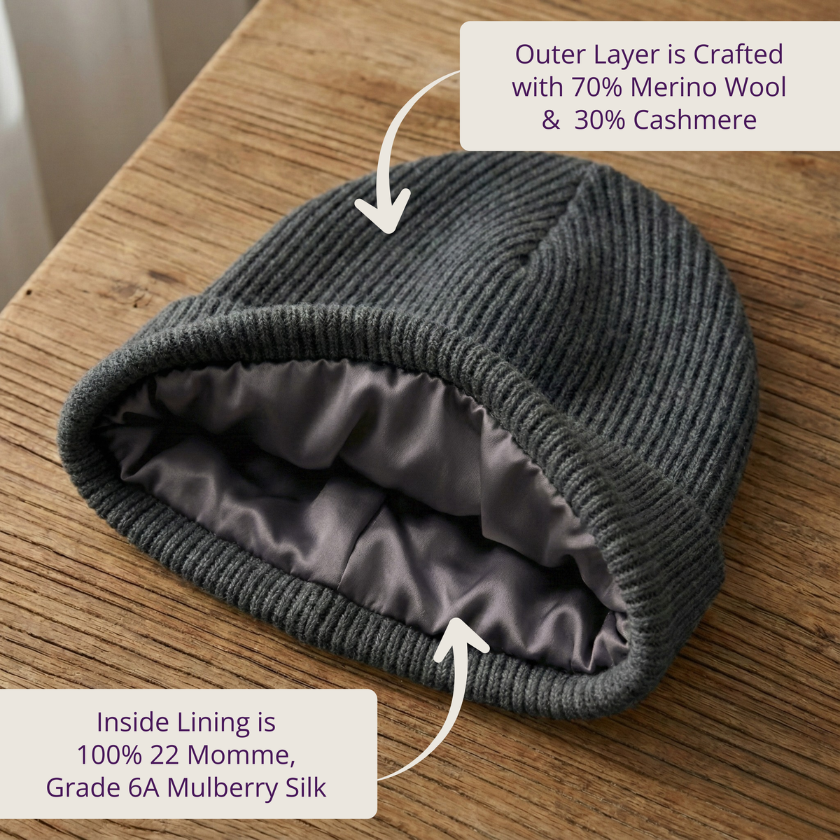 Gray knit beanie with merino wool and cashmere outer layer and silk lining on a wooden surface.