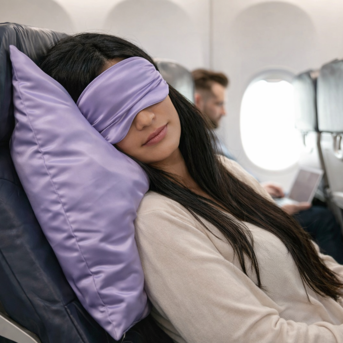 Woman sleeping on an airplane with a purple eye mask and pillow