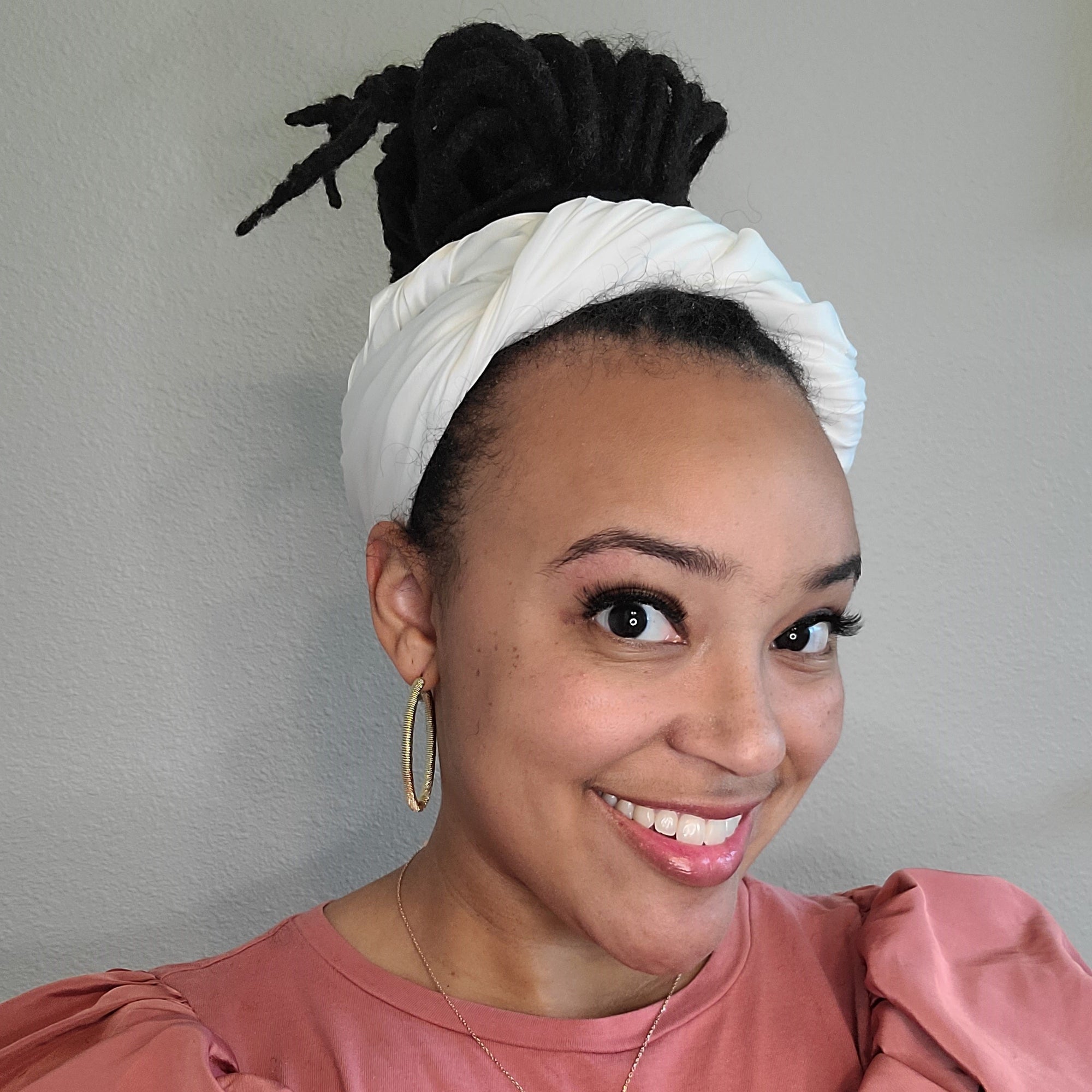 Black woman wearing an ivory silk head scarf as a headband wrap, fashionable style