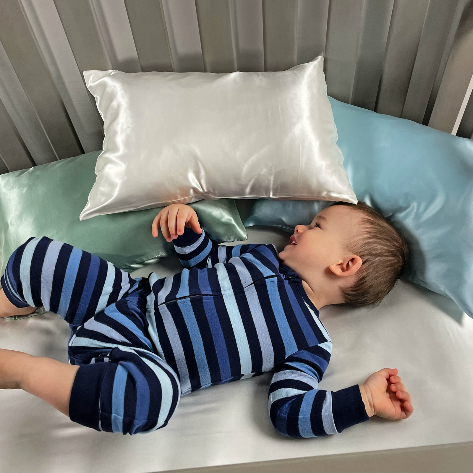 Baby sleeping on Mulberry Park Silks toddler silk pillowcase in ivory, green and blue.