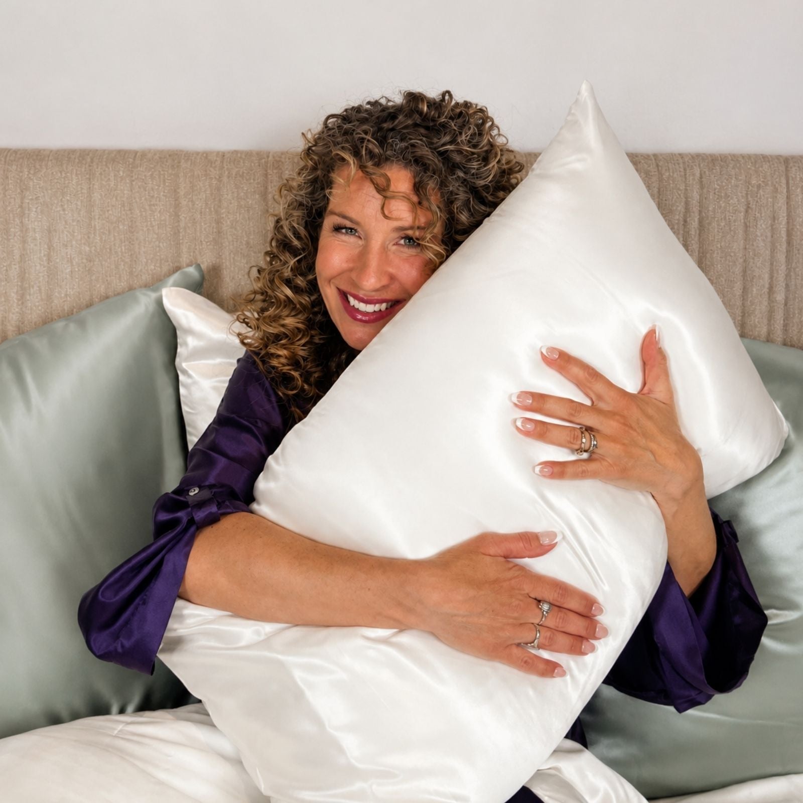 Woman hugging a large white pillow in a bedroom setting
